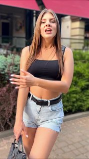 Молодая женщина в шортах и топе на городской улице, портретный кадр в уличном стиле, похожий на фрагмент ИИ‑сгенерированного видео.