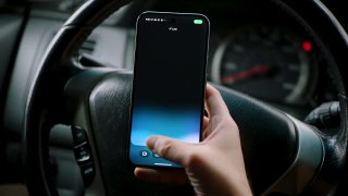 Человек держит смартфон в автомобиле — изображение иллюстрирует мобильные демонстрации новых возможностей поиска и ассистентов.