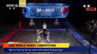 Ведущий на ринге между двумя роботов-бойцами; видно табло с китайскими символами и нижнюю графику «CMG WORLD ROBOT COMPETITION» трансляции.