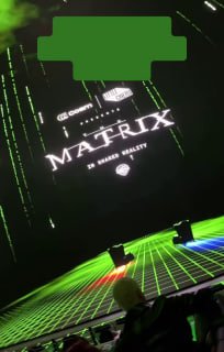 Внутри иммерсивного зала Cosm в Лос‑Анджелесе: огромный изогнутый LED‑экран с логотипом «Matrix», зелёными матричными графиками и зрителями на переднем плане.