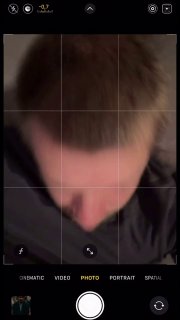 Снимок экрана камеры смартфона с размытым крупным планом головы; видно интерфейс съёмки и сетку для композиции кадра.