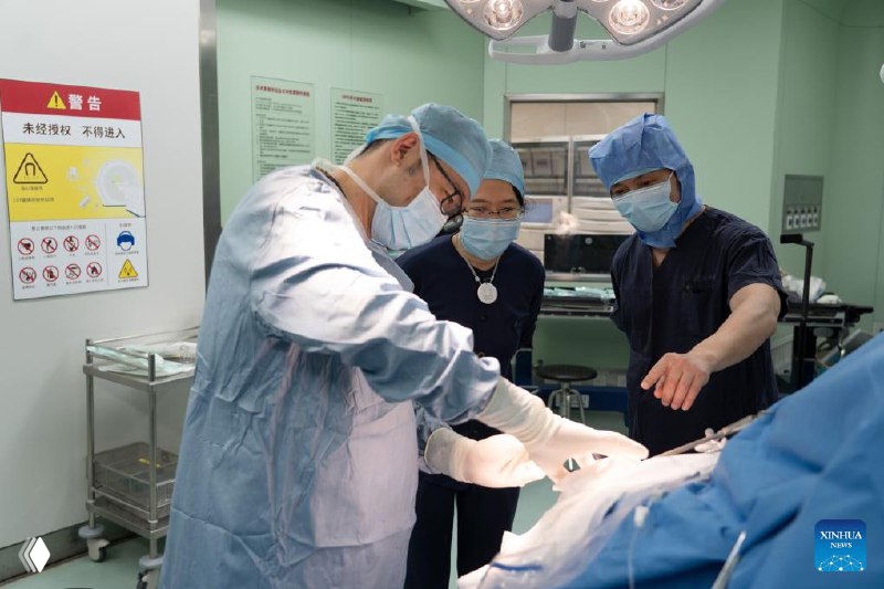 Хирургическая бригада в операционной во время операции по имплантации нейроинтерфейса: доктора в стерильной одежде за столом.