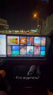 Фото салона LiXiang L7 с крупным центральным экраном мультимедиа, видна подпись «Кто водитель?» на экране, ночная улица за окнами.