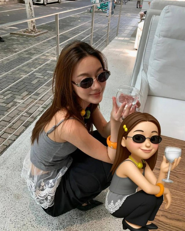 Женщина в солнечных очках сидит с бокалом, рядом добавлен 3D‑мемоджи с похожими очками и позой, кадр у окна или на террасе.