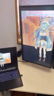 Рабочее место: ноутбук и большой вертикальный монитор, на экране которого отображается крупная аниме‑фигура, синхронизированная с проекцией.