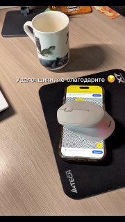 На фото лежит беспроводная мышь на экране смартфона с открытым приложением; видны коврик и кружка — иллюстрация трюка.