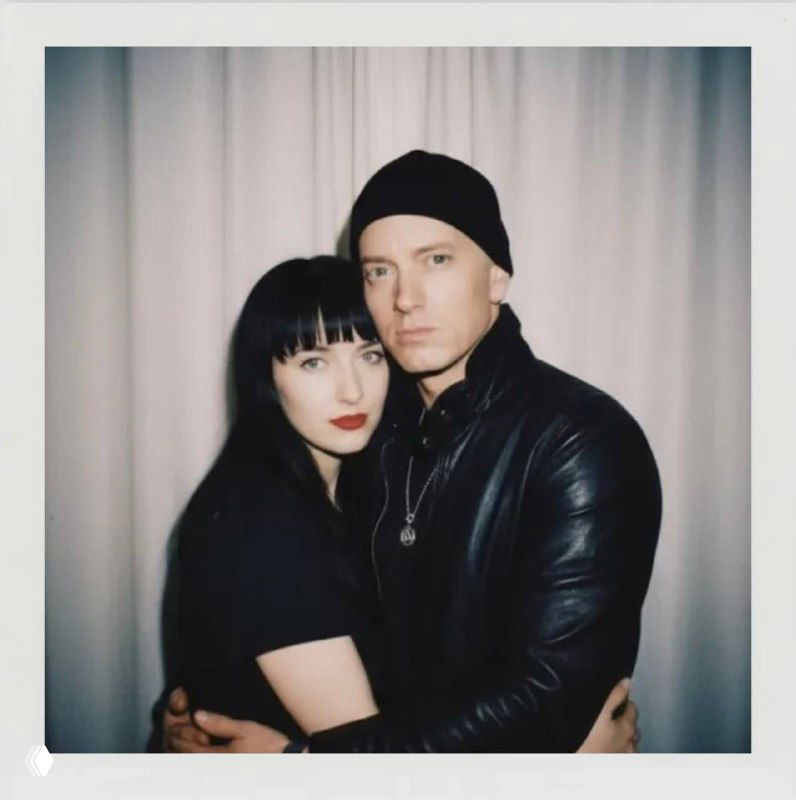 Полароидный кадр пары в тёмной одежде на светлом фоне; спокойная композиция, взгляд в камеру и интимная естественность момента.