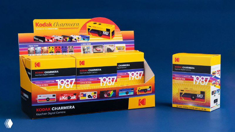 Дисплей с коробками Kodak Charmera: несколько упакованных мини-камер выставлены на прилавке в яркой упаковке с маркировкой 1987