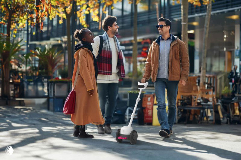 Молодые люди идут по городской улице, рядом одна из них проверяет работу трости Glidance в городских условиях — пример использования в реальной среде