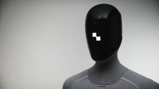 Крупный план головы робота Figure 03 с чёрной маской и серой тканевой «кожей», демонстрация дизайна головы и текстуры корпуса в студийной обстановке.