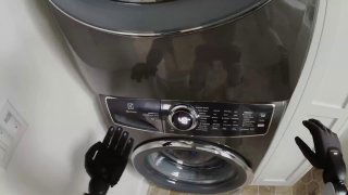 Руки робота Figure 03 рядом со стиральной машиной, видны манипуляторы и гибкие пальцы с сенсорными элементами, бытовой контекст использования робота.