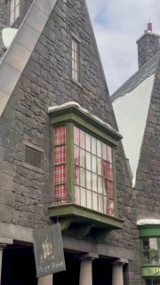 Фрагмент фасада домов Хогсмид с украшенными крышами и окнами, архитектура парка стилизована под сказочную деревню Гарри Поттера.