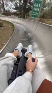 Кадр с горки-аттракциона: ноги пассажира в спортивной обуви, металлическая трасса и окружающие деревья — развлечение на маршруте осмотра.