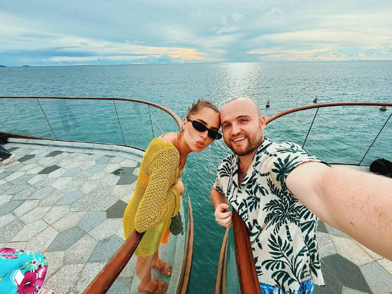 Пара на палубе лодки у кромки моря: панорамный вид, бирюзовая вода и расслабленная прогулка по океану возле острова.