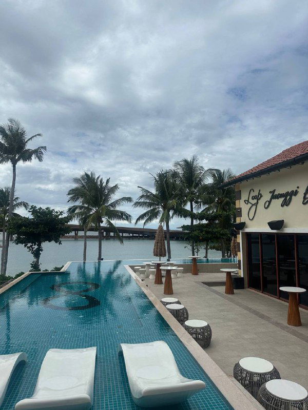 Бассейн у берега с шезлонгами и пальмами: спокойный курортный уголок на острове для отдыха и работы вдали от города.