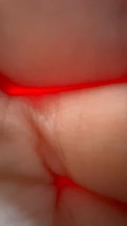 Крупный кадр пальца, закрывающего объектив, с красноватым свечением и размытым фоном; случайный бытовой снимок во время съёмки на телефоне.