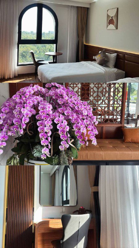 Интерьер номера отеля с кроватью и арочным окном, на переднем плане крупная композиция орхидей — уютный номер с видом и спокойной атмосферой.