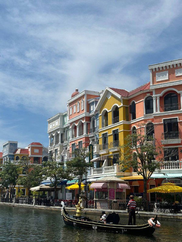 Ряд ярких разноцветных зданий вдоль канала на Фукуоке, лодки у причала и отражение в воде — живописная туристическая улица для прогулок.