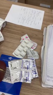 Несколько упаковок таблеток и медикаментов на столе рядом с документами и ручкой — препараты, выданные после приёма у стоматолога во Вьетнаме.