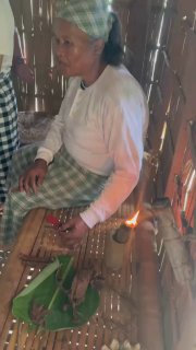 Пожилая женщина внутри хижины за простым домашним занятием: близкий план рук и традиционных предметов быта на деревянном полу фермерского дома