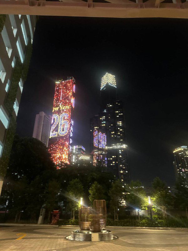 Ночной городской пейзаж Куала‑Лумпура с подсвеченными высотками и яркими цифровыми панелями — вечерняя атмосфера мегаполиса.