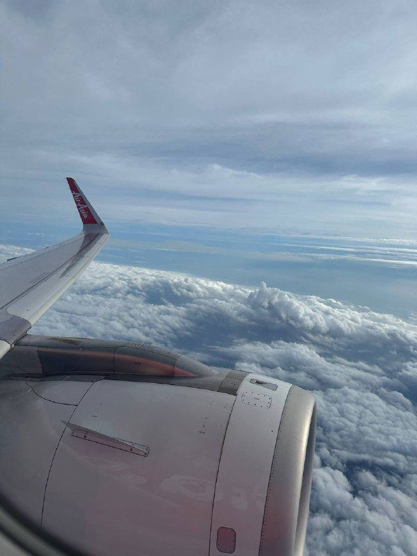 Вид из окна самолёта на крыло и обширное облачное поле под ним — типичный кадр перелёта между странами, ощущение пути и путешествия.