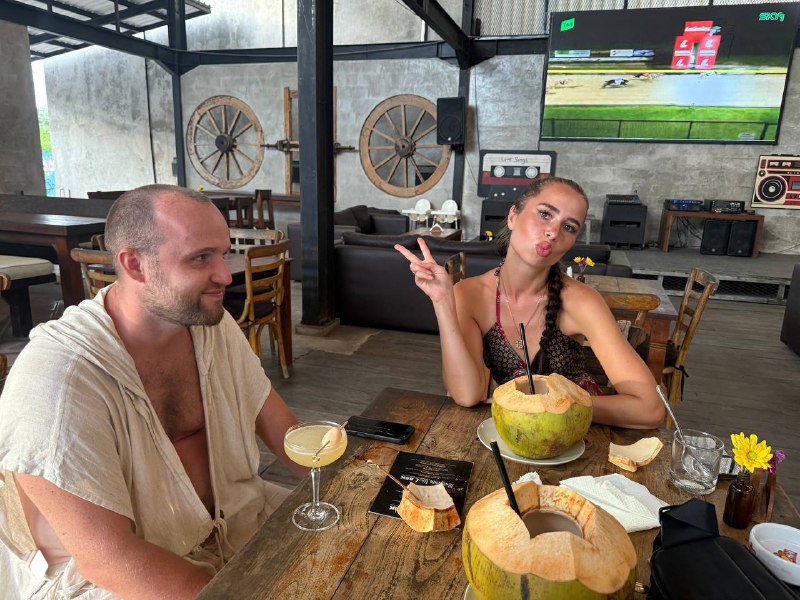 Пара за столом в кафе с кокосами и коктейлями: расслабленная обстановка, местная еда и дружеские разговоры во время путешествия.