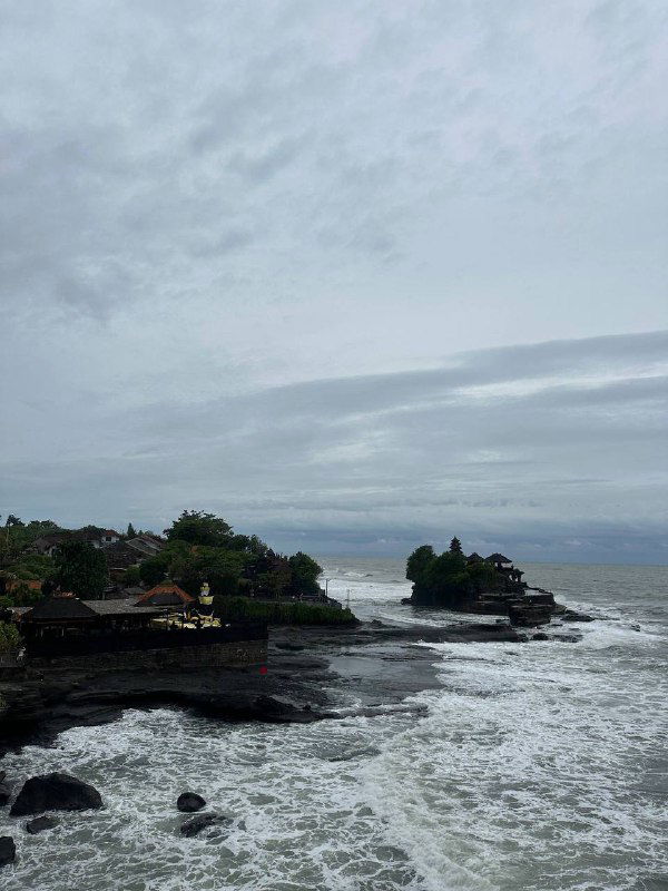Морской пейзаж с прибрежными скалами, храмом у воды и пасмурным небом — атмосферный вид побережья на фоне волн.