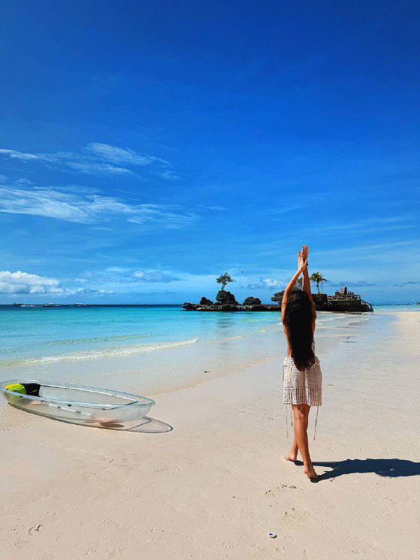 Пейзажная фотография: женщина на тропическом пляже с поднятыми руками на фоне белого песка и бирюзовой воды — настроение свободы и достижения целей.