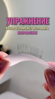 Крупный план: руки мастера держат тестовую ленту ресниц на светлом фоне; видно направление изгиба ресниц и текст «УПРАЖНЕНИЕ», иллюстрирующий тренировку навыка.