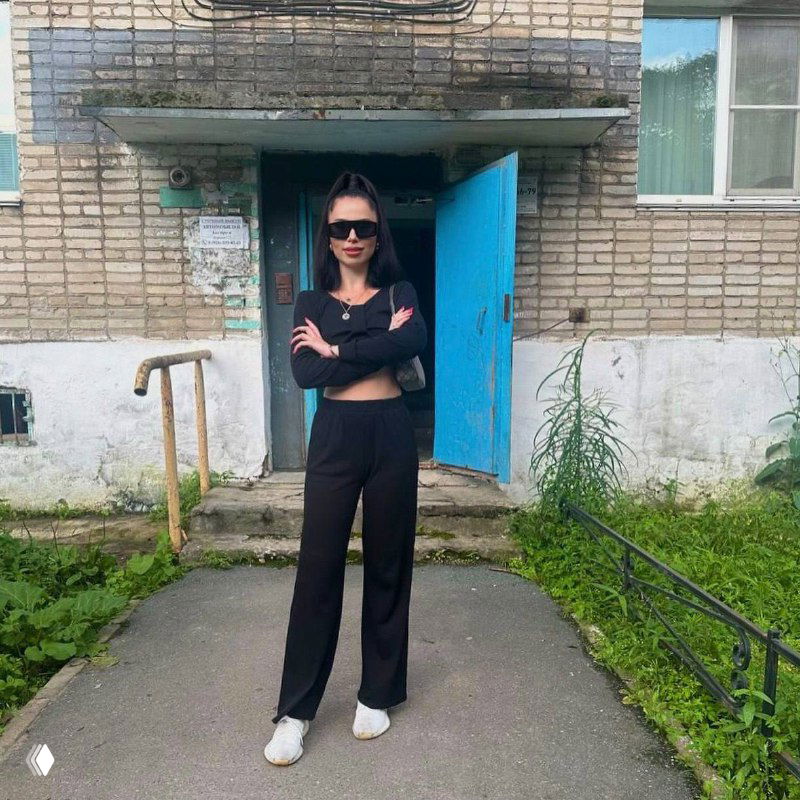 Современное фото автора у входа в типичный многоквартирный дом посёлка: повседневный образ, который подчёркивает корни и искренность истории.