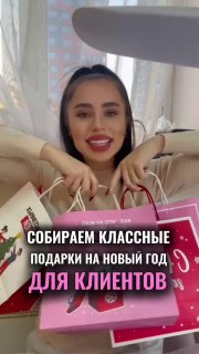 Улыбающаяся мастерица по наращиванию ресниц с несколькими праздничными подарочными пакетами, текст о подборе подарков для клиенток.