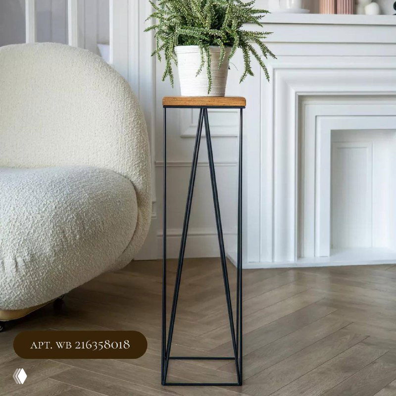 Тонкая треугольная подставка на ножках с деревянной площадкой, на ней небольшой горшок с зелёным растением рядом с креслом в гостиной