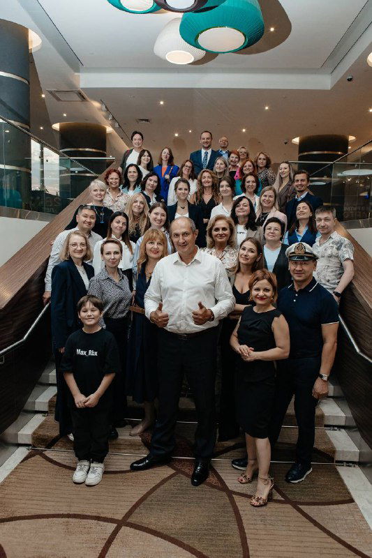 Большая групповая фотография участников конференции по медиации на лестнице отеля: организаторы и гости улыбаются и позируют для совместного кадра.