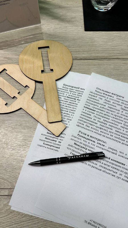 Крупный план реквизита бизнес‑игры: деревянные ключи, ручка и распечатанный кейс на столе — элементы, используемые в упражнении по переговорам.