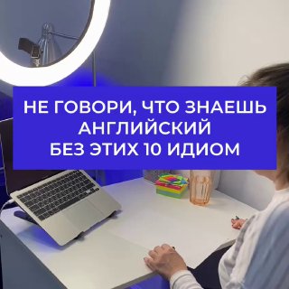 Рабочее место с ноутбуком, кольцевой лампой и человеком; на фото крупная надпись о необходимости знать 10 однословных английских идиом.