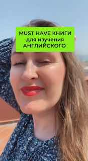 Крупный план автора Марии Малышевой на открытом воздухе; на фото зелёный блок с надписью 'MUST HAVE книги для изучения английского', улыбка автора и небо на фоне.