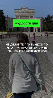 Человек идёт по площади к зданию вечером; видно зелёный блок «мудрость дня» и мотивационная надпись белым текстом.
