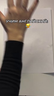 Снимок вертикального кадра: рука над белым листом бумаги, на изображении текст «УЧИМ АНГЛИЙСКИЙ», иллюстрация короткого видео-урока и практики.