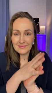 Мария Малышева в кадре: крупный план ведущей эфира в домашней студии, спокойная улыбка, жесты руками, фиолетовая подсветка и лампа на заднем плане.