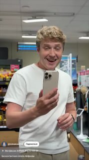 Молодой человек в магазине держит iPhone у кассы возле терминала — фото иллюстрирует тему оплаты по BLE и вопросы безопасности.