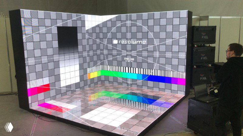 Угловой светодиодный пол и экран с тестовой цветовой шкалой: проверка отображения и настройка изображения, рядом оператор у пульта.