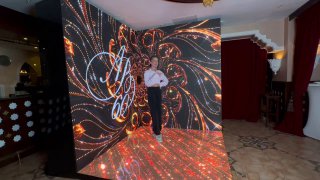 Угловая LED‑фотозона с анимированным узором на экране; посетитель в кадре демонстрирует эффект движения для буллет‑тайм съемки.