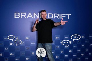 Человек позирует на фоне синего пресс‑волла с логотипом Brand Drift: пример готового кадра из 3D Bullet Time фотозоны.