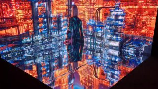 Угловая LED‑фотозона с крупной яркой оранжево‑индустриальной графикой; видна отражающая поверхность пола и силуэт человека в кадре.