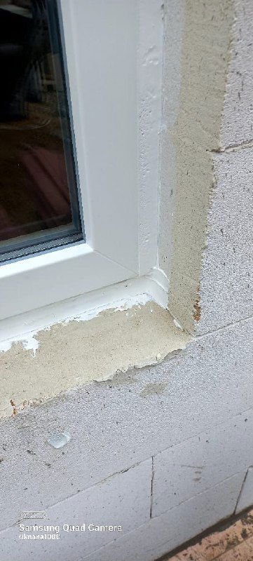 Фрагмент оконного проема в газобетонной стене: нанесённый наружный герметик и слой пены по кромке проёма, видны следы монтажных работ.