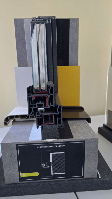 Поперечный разрез стеклопакета и рамы на стенде: демонстрация толщины профиля, уплотнений и опоры для подоконника в тёплом решении.