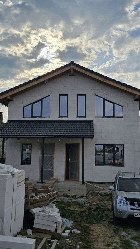 Фасад дома с установленными окнами разных размеров, вид снаружи показывает общую компоновку и контекст работ по остеклению.