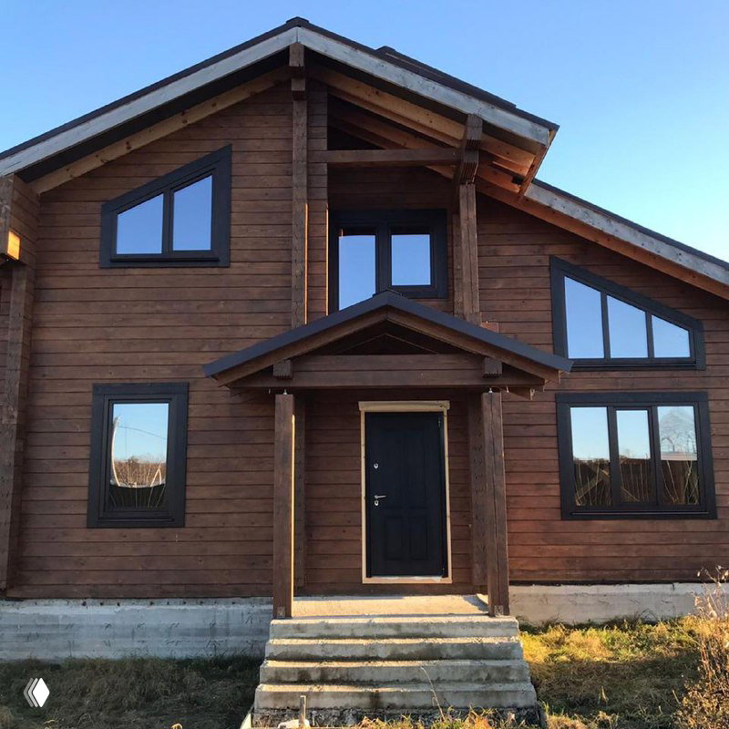 Фасад деревянного дома с тёмной отделкой и симметричными окнами — пример комбинированного дизайна и монтажных решений.