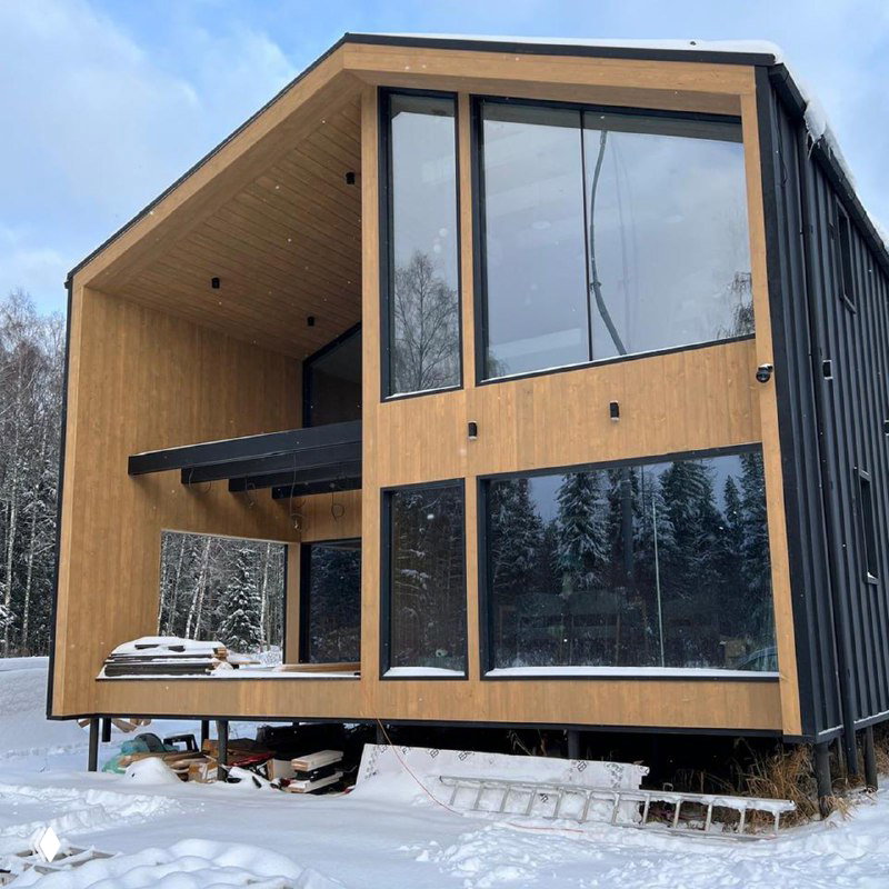 Современный дом с контрастной облицовкой и большими зеркальными окнами в деревянном корпусе — пример архитектурного остекления.